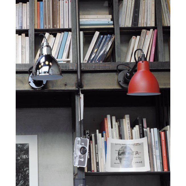 Wandspot La Lampe Gras op de boekenkast, links een verchroomde kap en rechts een gematteerde rode kap